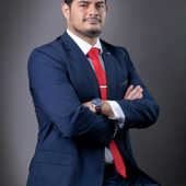 Professional portrait of a businessman in a suit with red tie, arms crossed.