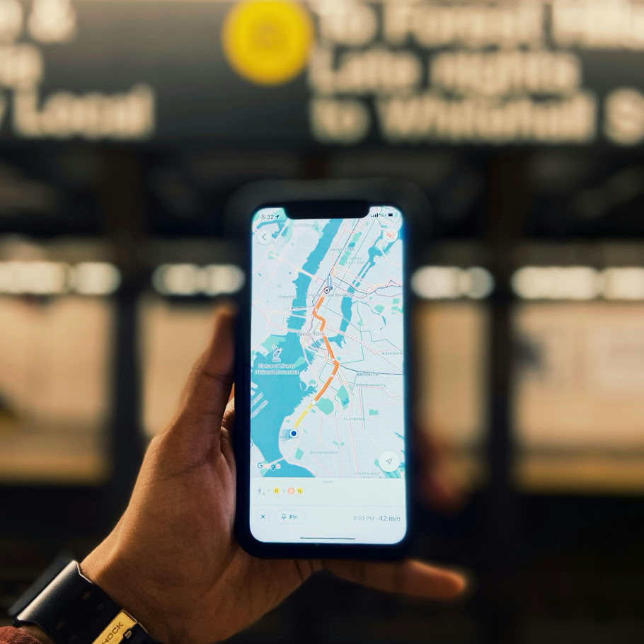 A person holds a smartphone displaying a map of NYC inside a subway station.